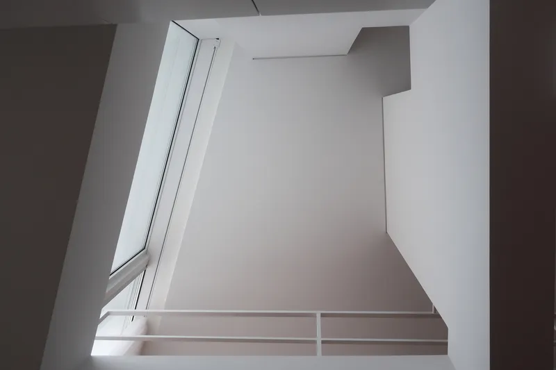Upward view of a double-height void with angled clerestory windows and a white railing