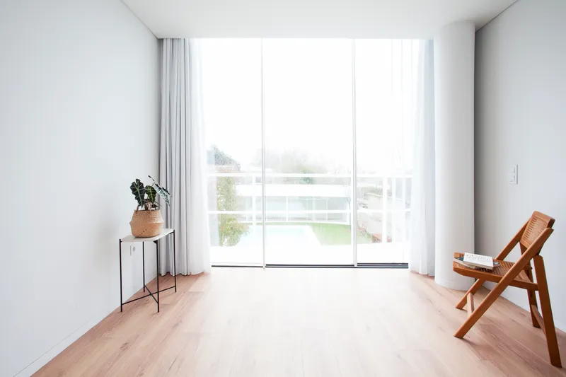 Living room with floor-to-ceiling glass overlooking a lawn under overcast skies