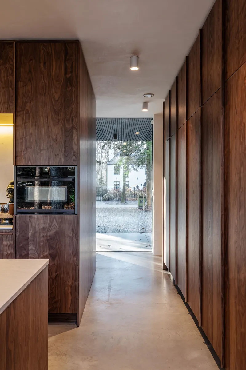 Corridor with walnut millwork walls and polished concrete floor leading to a glass door