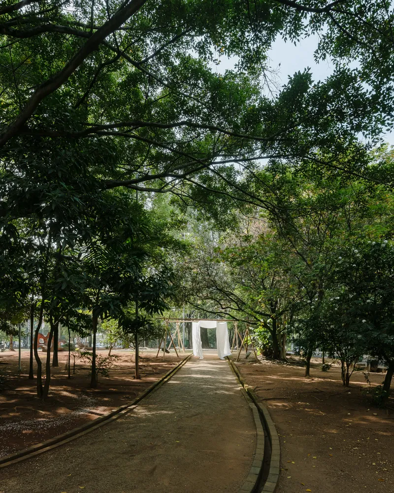 Path through a tree grove leading to a white cubic pavilion in the distance