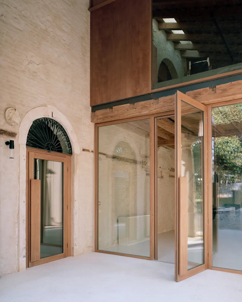 Open timber-framed glass doors with arched transom window and exposed beam mezzanine above
