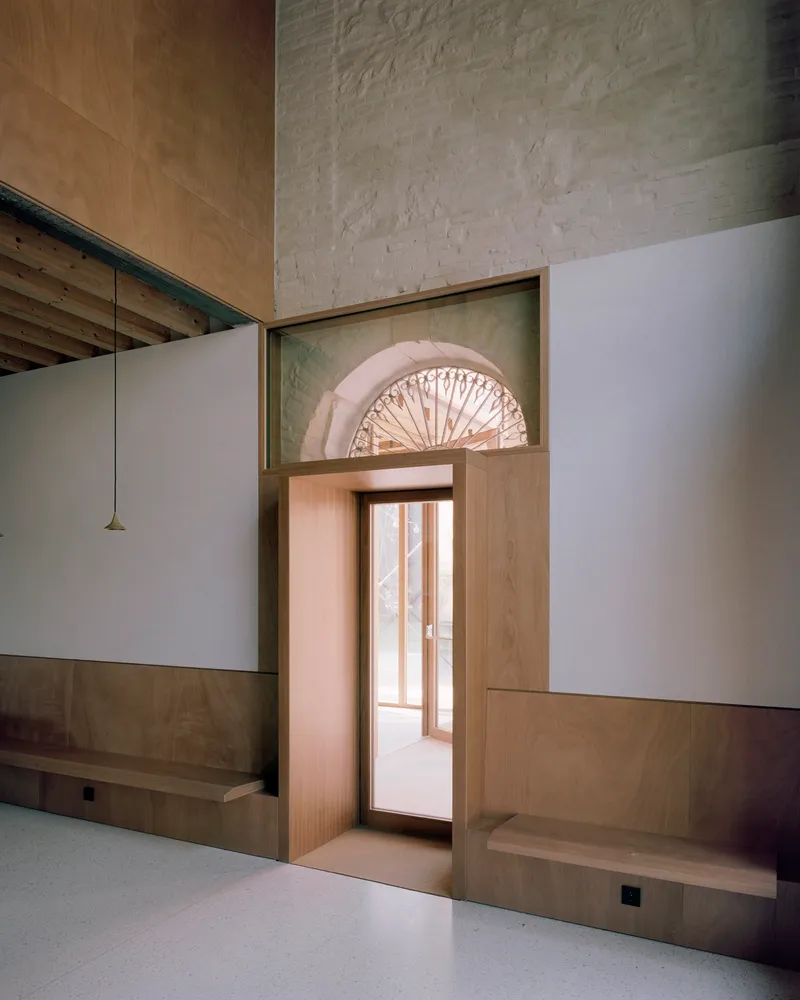 Interior view of timber-framed doorway with decorative fanlight in existing stone wall