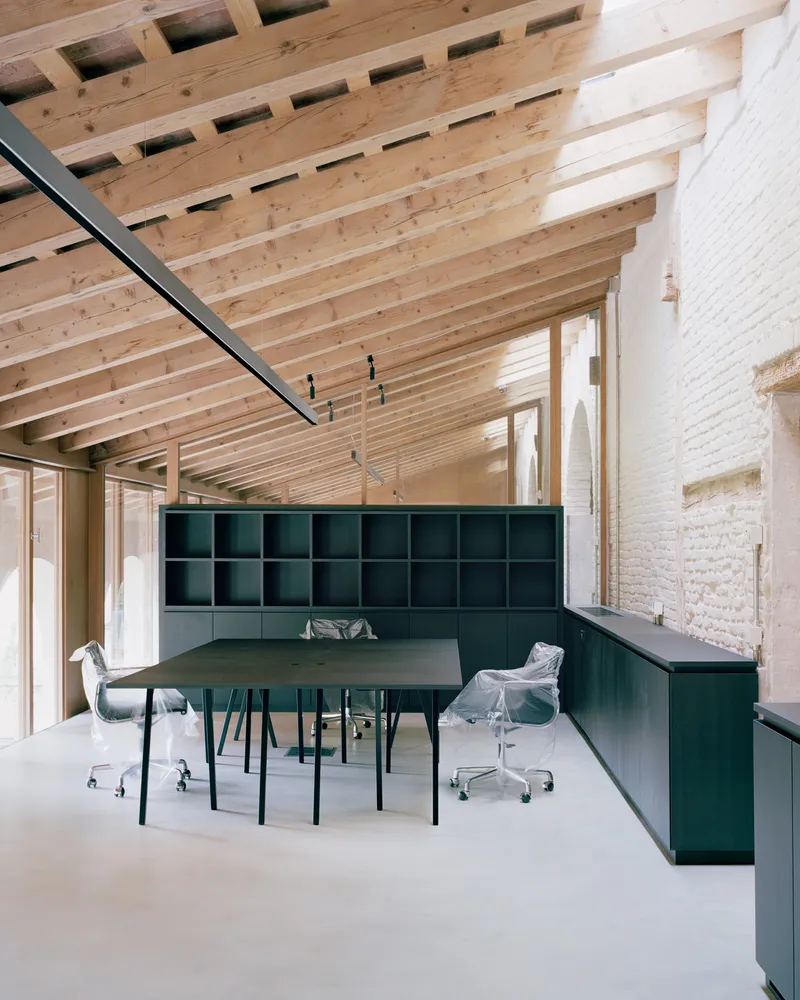 Conference room with green cubby wall and exposed timber joist ceiling visible through skylight openings above