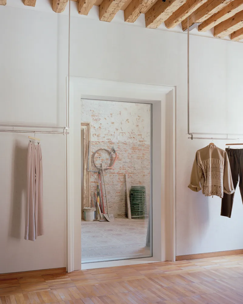 Doorway framing view into room with painted white brick wall and herringbone wood flooring in foreground