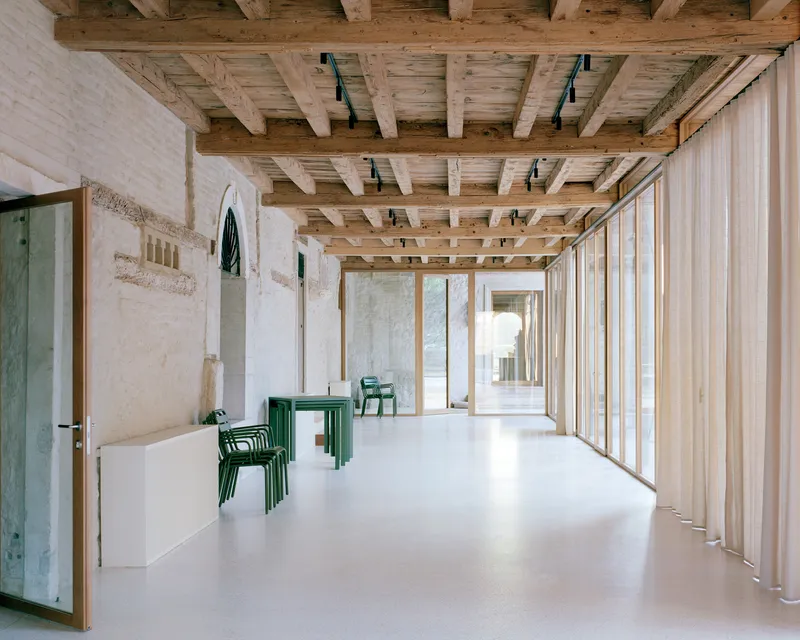 Interior corridor with exposed timber beam ceiling and vertical timber cladding along white resin floor