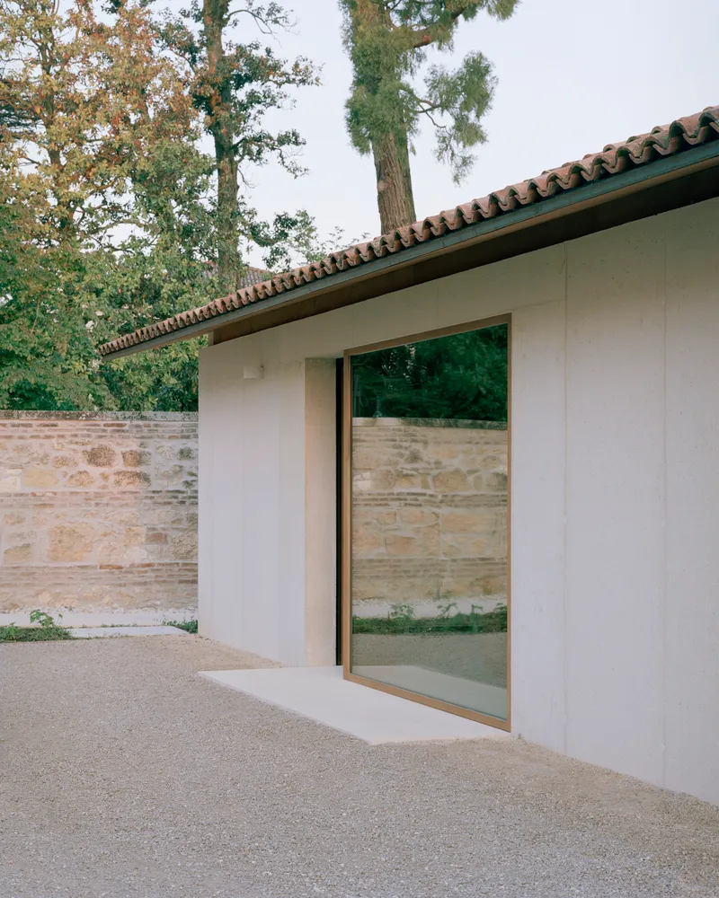 Sliding glass door set into a white rendered wall beneath a clay tile roof
