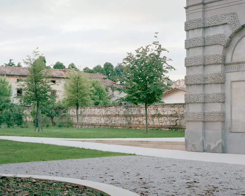 View across the gravel terrace toward the rusticated stone tower and garden walls with new planting