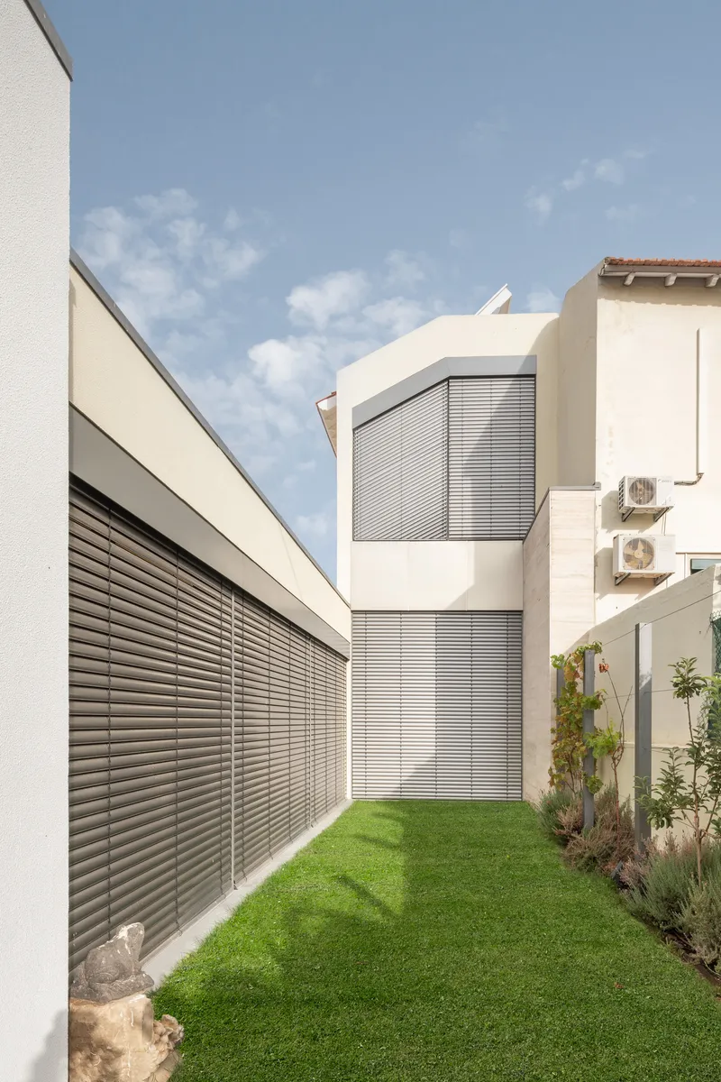 View along courtyard lawn showing horizontal louvers screening the glazed facades on both levels