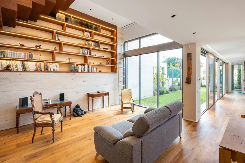 Living room with timber shelving wall and floor-to-ceiling glass opening to garden