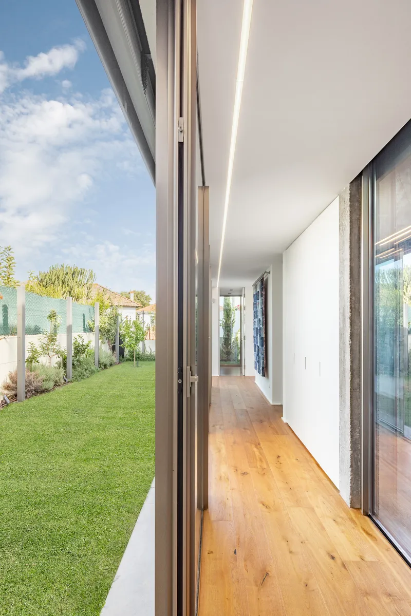 Corridor with timber floor and sliding glass wall opening to the lawn beyond