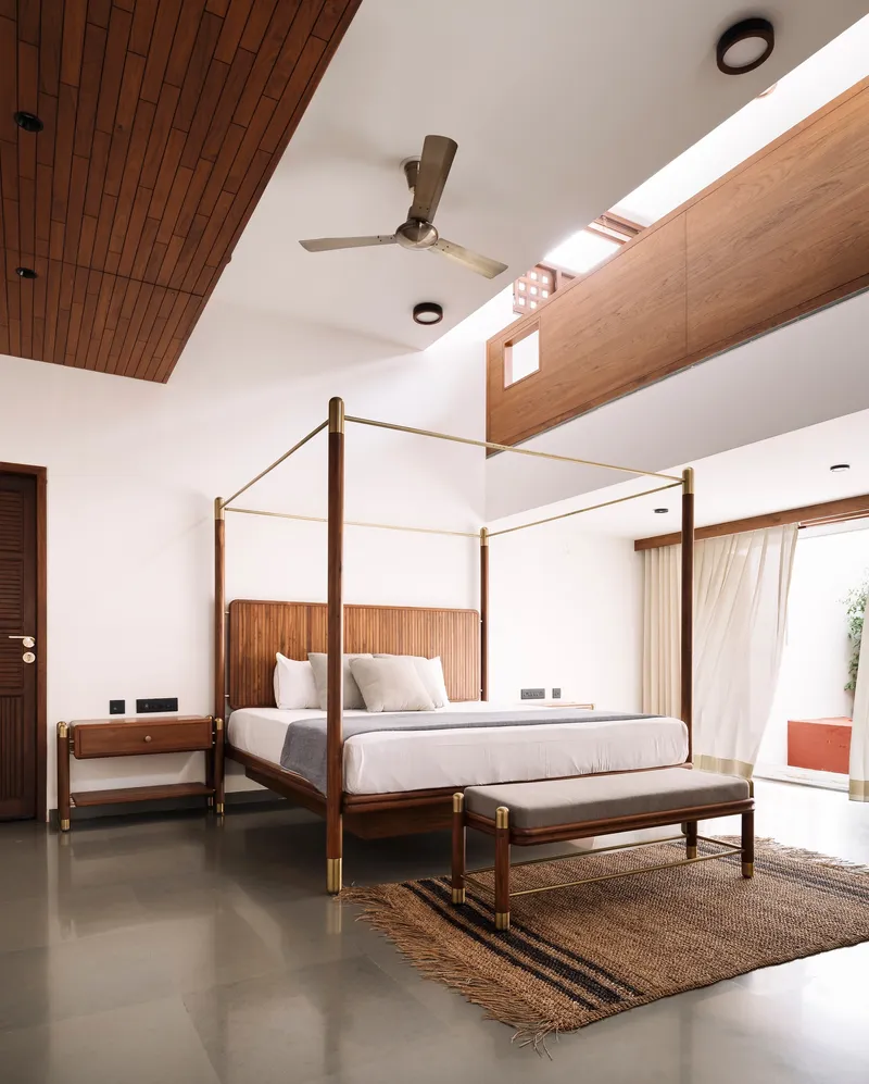 Bedroom with brass canopy bed beneath timber ceiling panels and clerestory windows above