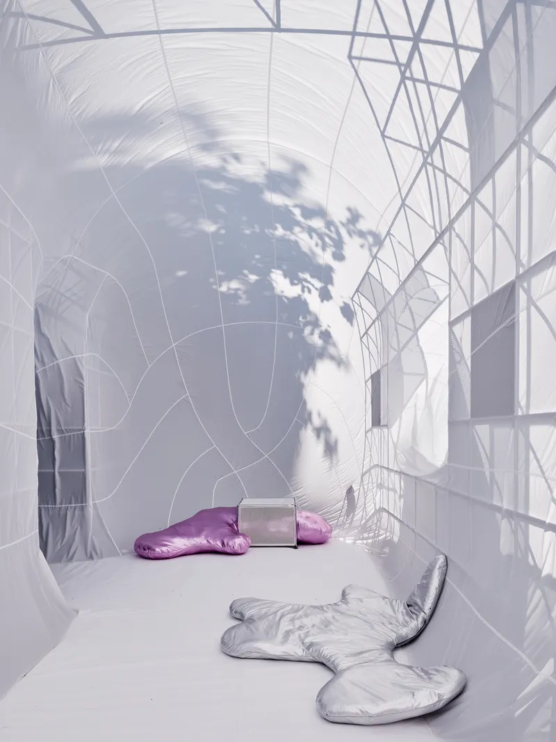 White fabric chamber with tree shadow cast across the membrane surface and two silver cushions on floor
