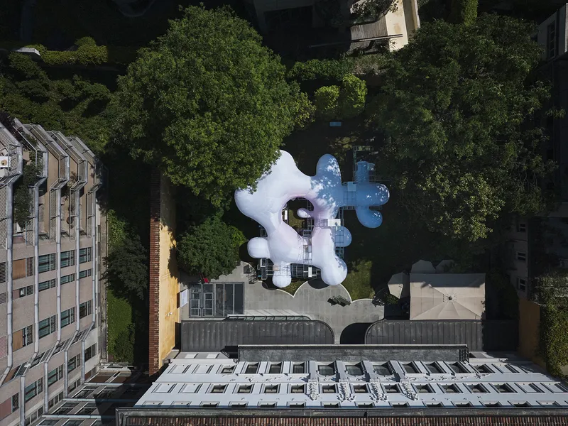Aerial view of the white inflatable pavilion with three bulbous lobes set among green trees