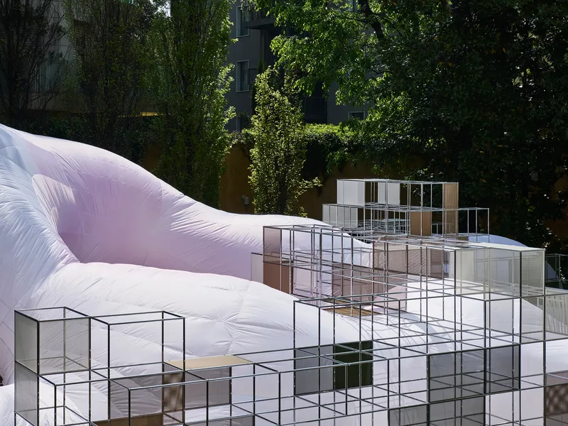 Stacked glass and metal display boxes arranged before the white inflatable structure in daylight