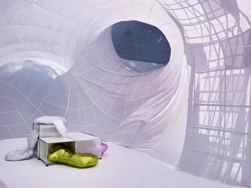 Inflatable chamber with a circular portal and yellow cushions beside metal furniture under soft light