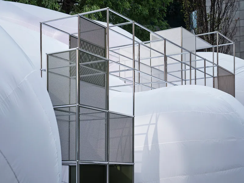 Aluminum frame shelving system with mesh and glass panels rising above inflatable dome structures