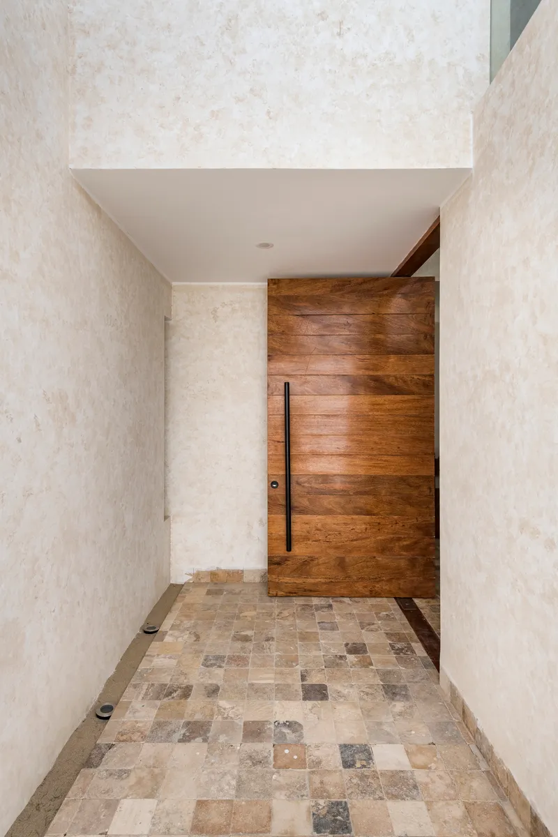 Covered entry vestibule with horizontal timber door and multicolored stone tile floor