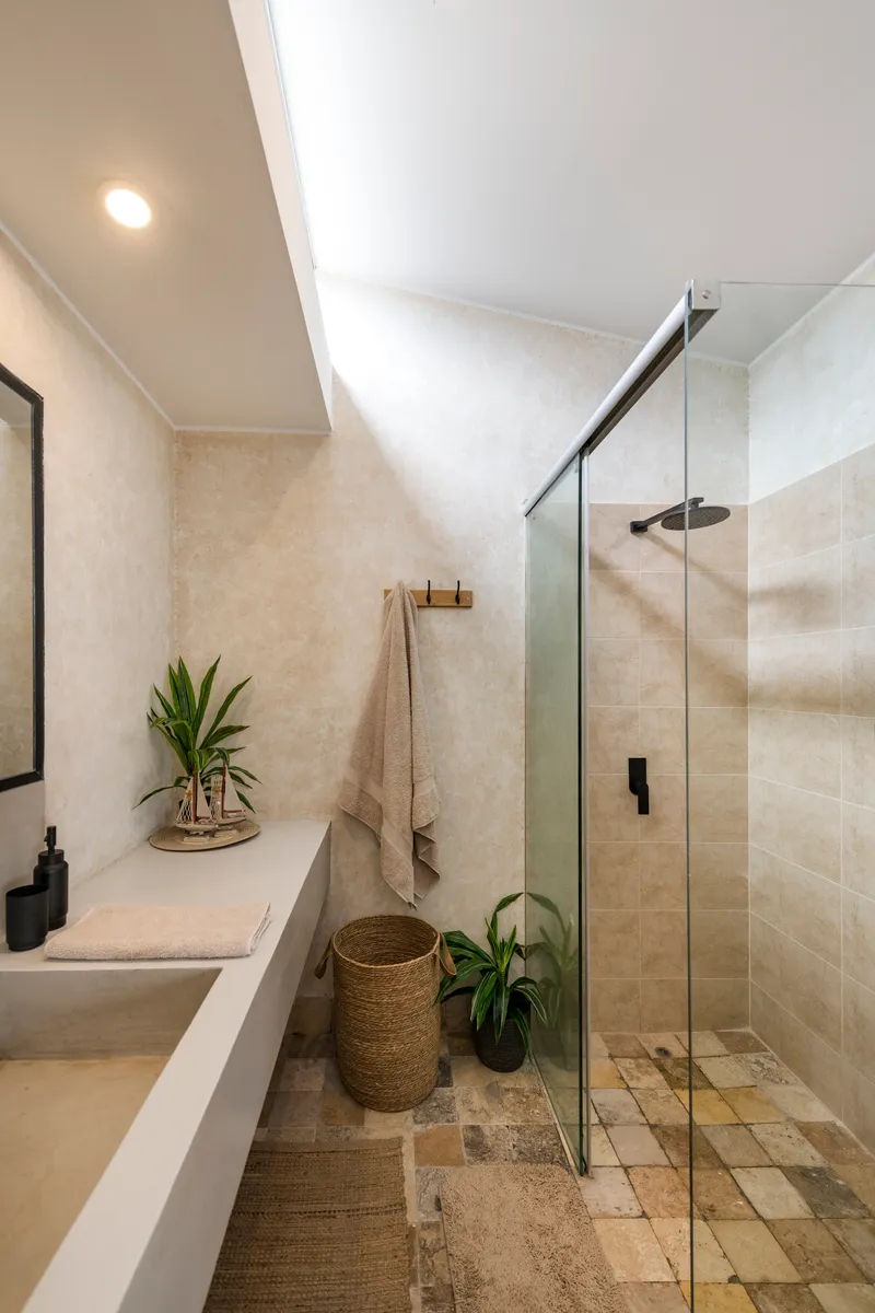 Bathroom with walk-in glass shower enclosure and skylight above a cast concrete vanity