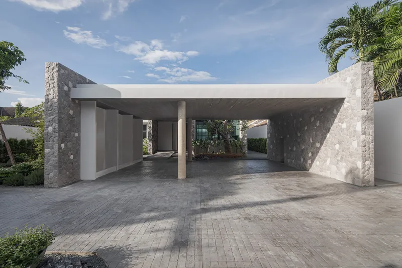 Covered carport with flat concrete canopy supported by stone-clad piers and a single round column