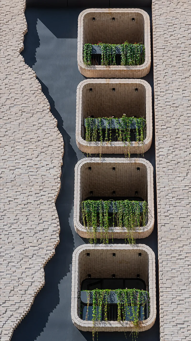 Aerial view of four stacked balconies with exposed brick ceilings and planters between black metal railings
