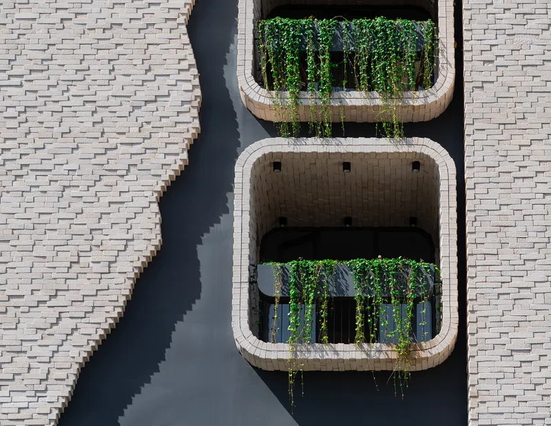 Overhead view of two stacked balconies with rounded brick frames and trailing vines