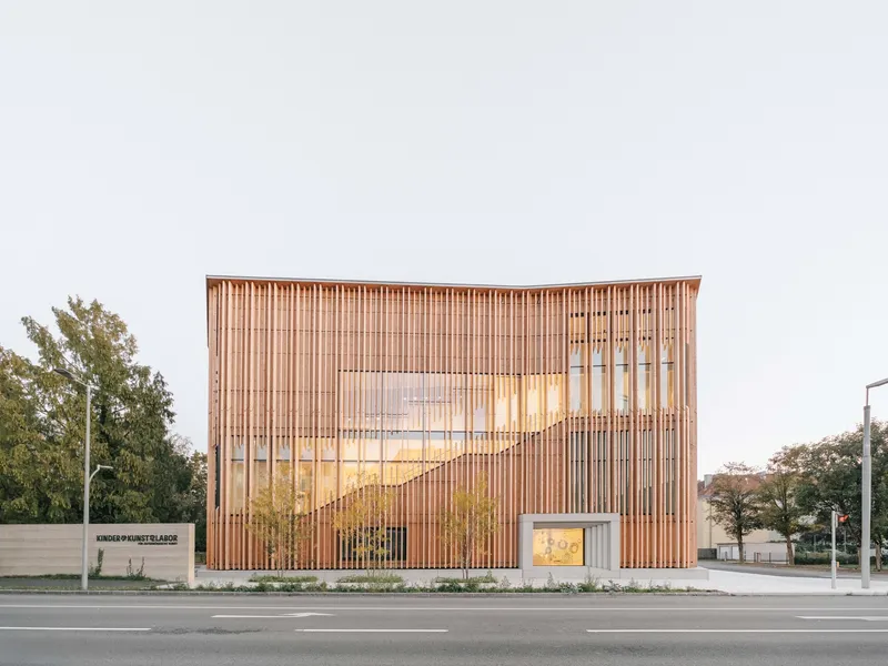 Street view of the vertical timber slat facade with glazed openings under overcast light