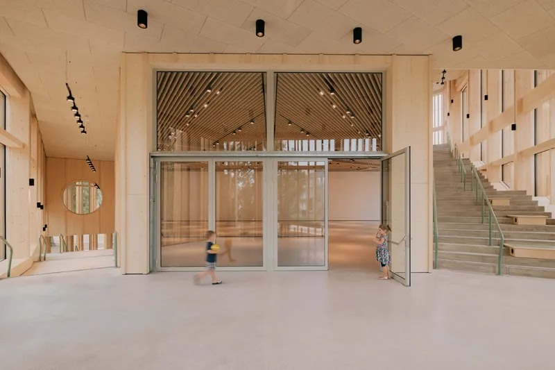 Ground floor lobby with glass doors and children moving through the polished concrete space