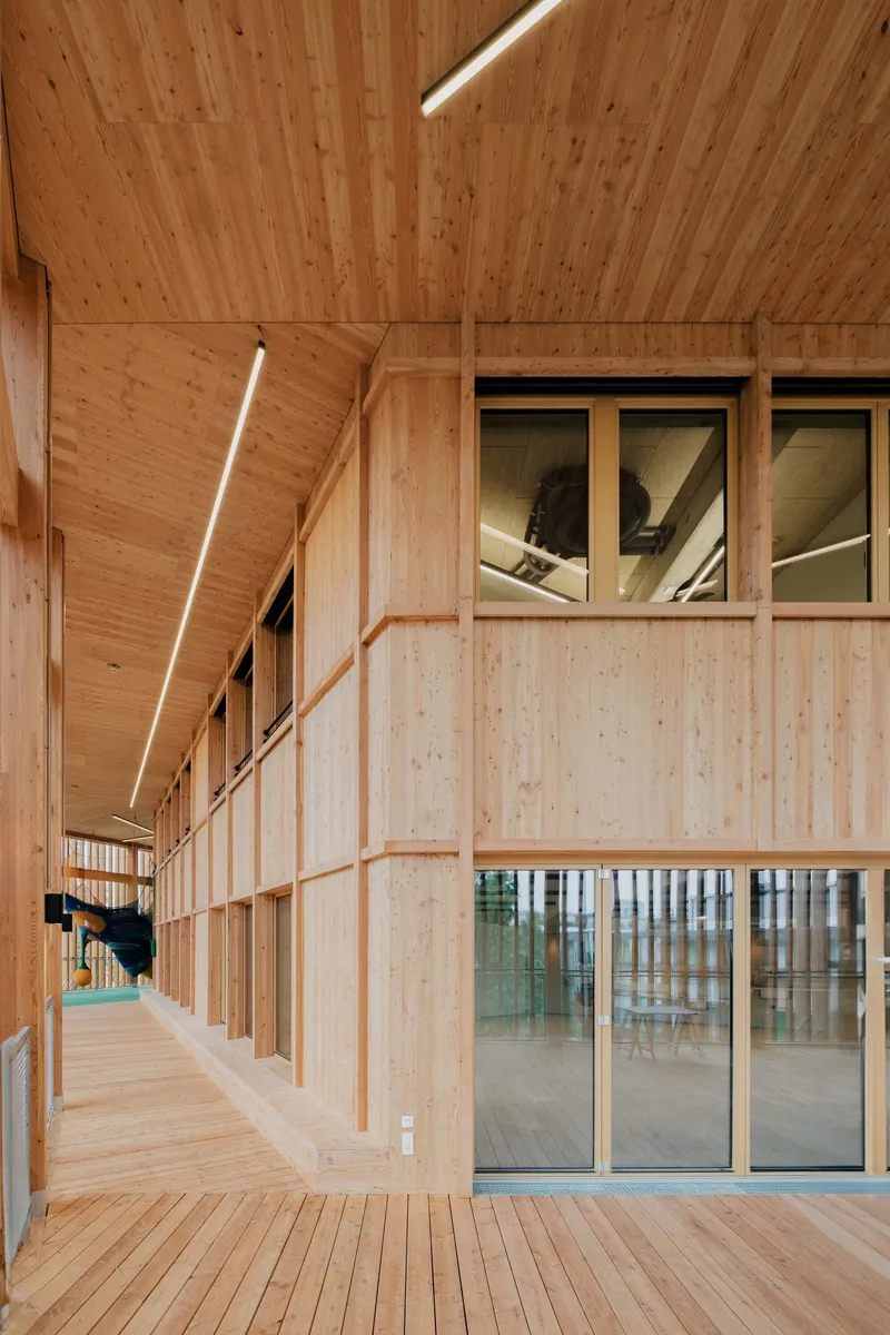 Interior corridor with cross-laminated timber walls, ceiling panels and linear strip lighting