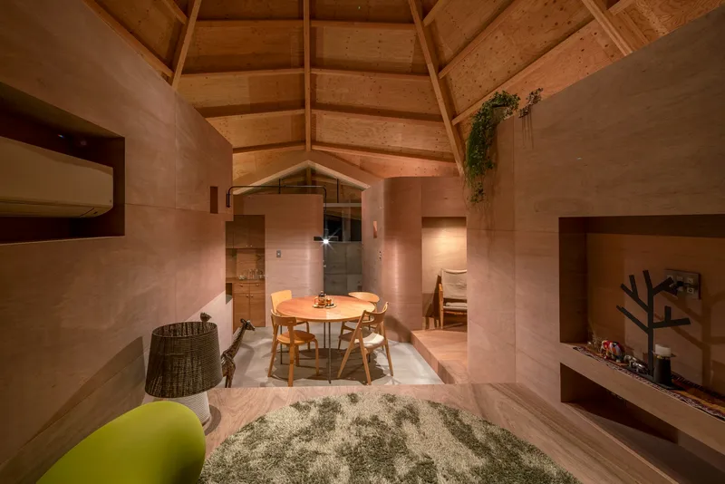 Evening view of the interior showing the dining area beneath the timber ceiling with pendant lights and greenery