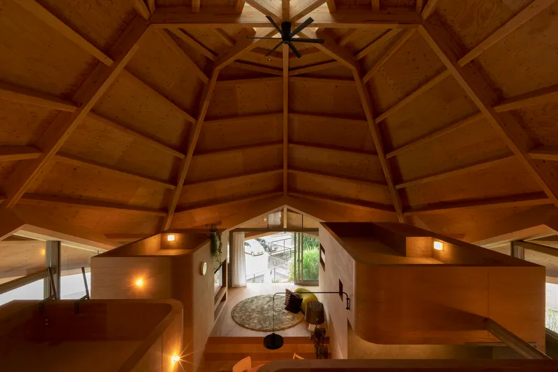 Overhead view into the plywood-lined living space illuminated by warm sconces at dusk