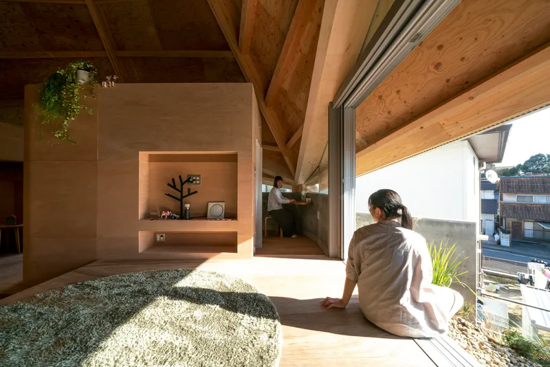 Person seated in an alcove opening to a gravel courtyard with afternoon sunlight streaming inside