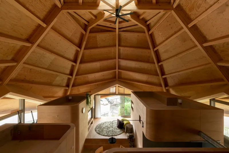 View down into the plywood interior volumes from an upper platform beneath the faceted timber ceiling