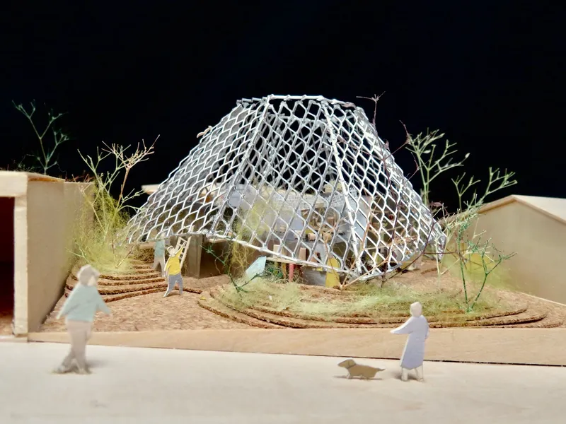 Physical model showing lattice roof structure over planted courtyard garden with miniature figures and dog