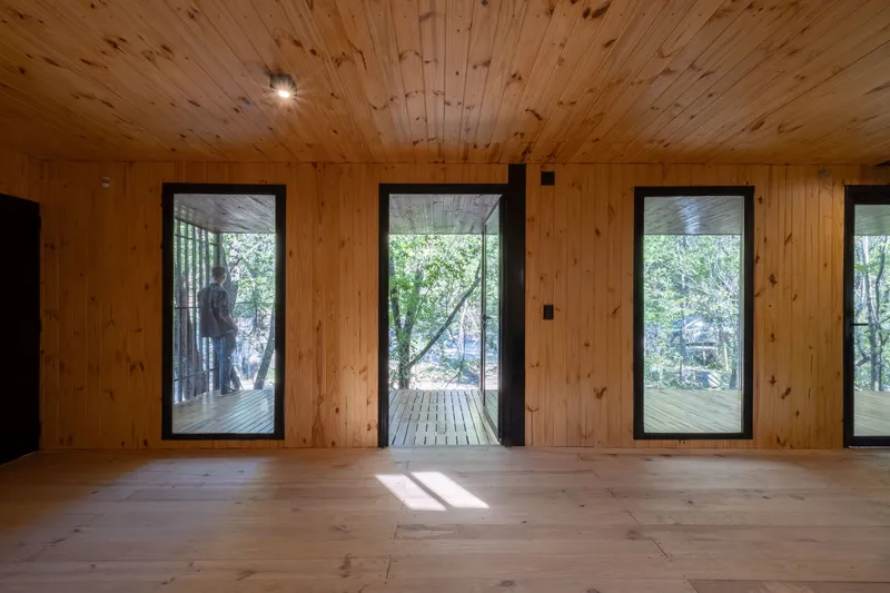 Pine-lined interior with tall glazed doors opening to a timber deck