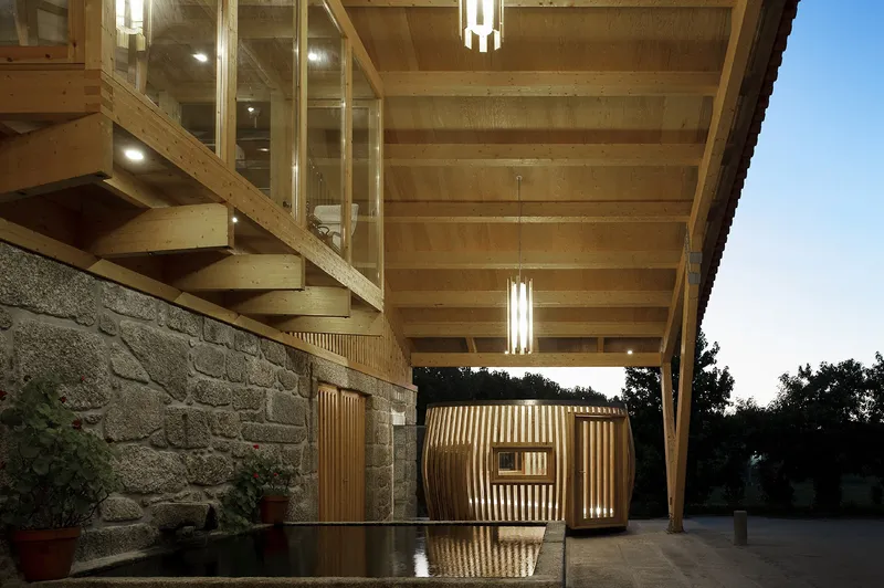 Covered porch with exposed timber beams and stone wall reflecting in wet pavement after rain