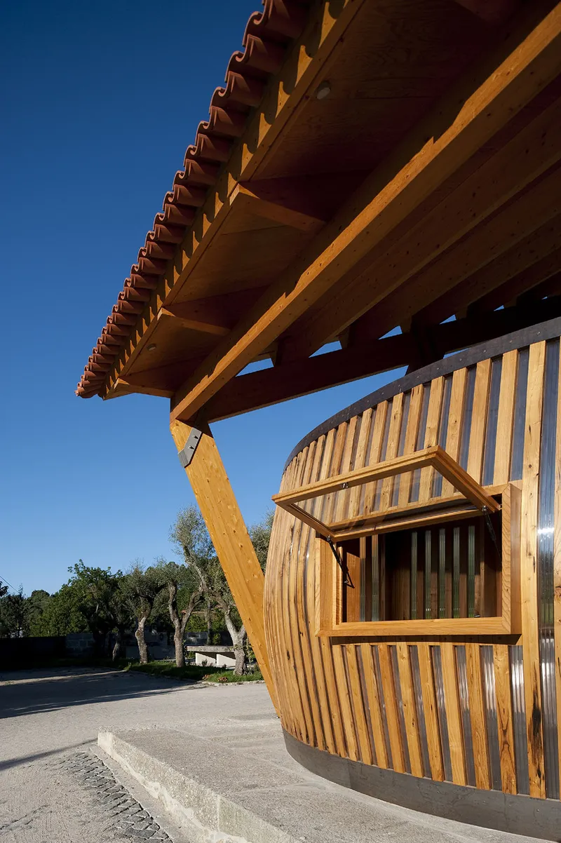 Corner detail of the timber overhang with exposed diagonal brace and slatted screen window in afternoon sun