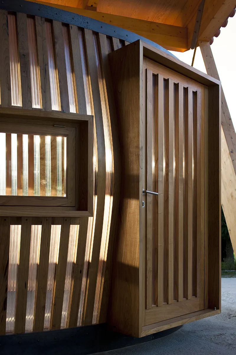 Timber slatted entrance door and window screen casting sharp shadows in direct sunlight