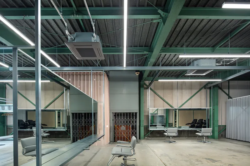 Central salon station area with fabric curtain divider and lattice metal gates flanking concrete column