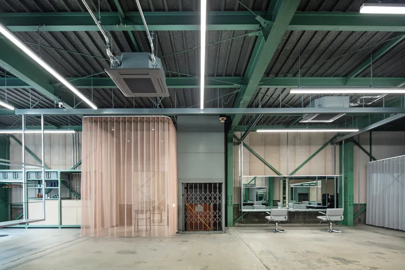 Closed translucent pleated curtain screening the corrugated wood volume under linear fluorescent lighting