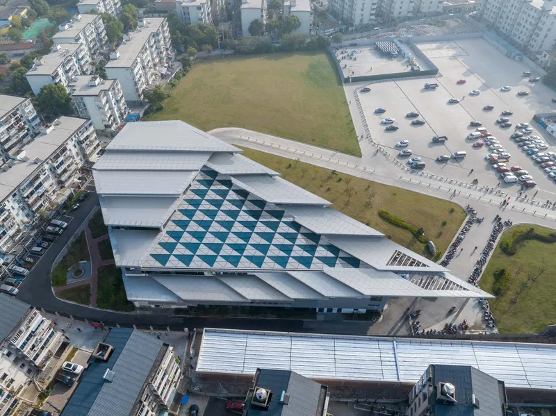 Aerial view of the stepped zinc roof with diagonal blue-and-white checkered glass insert beside a parking lot