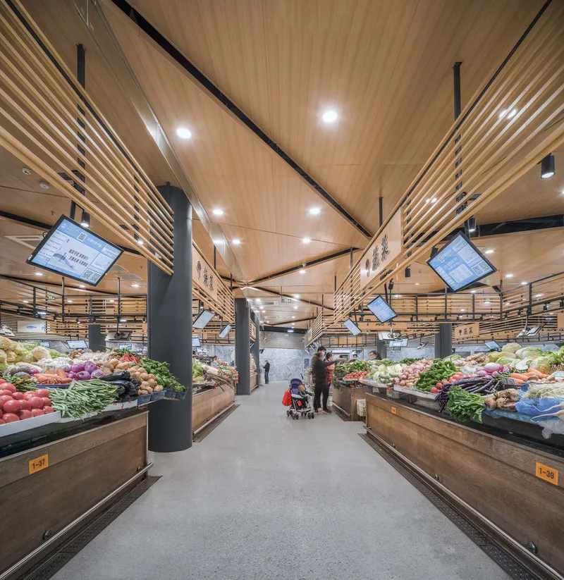 Central aisle with timber ceiling panels, suspended screens and vegetable displays flanking both sides