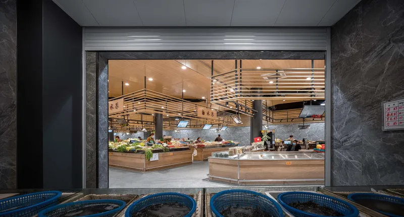View through raised metal shutter into the market hall from a dark marble corridor