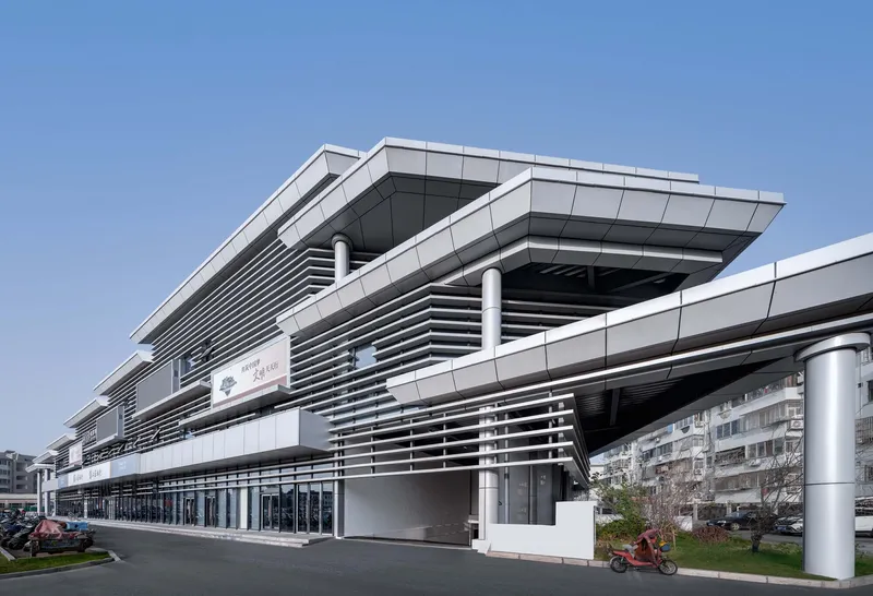Street-level view of the stacked horizontal metal louvers wrapping the facade with cylindrical columns at grade