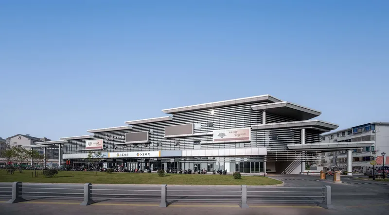 Street view of the multilevel building with horizontal louvers and deep overhanging roofs under clear blue sky