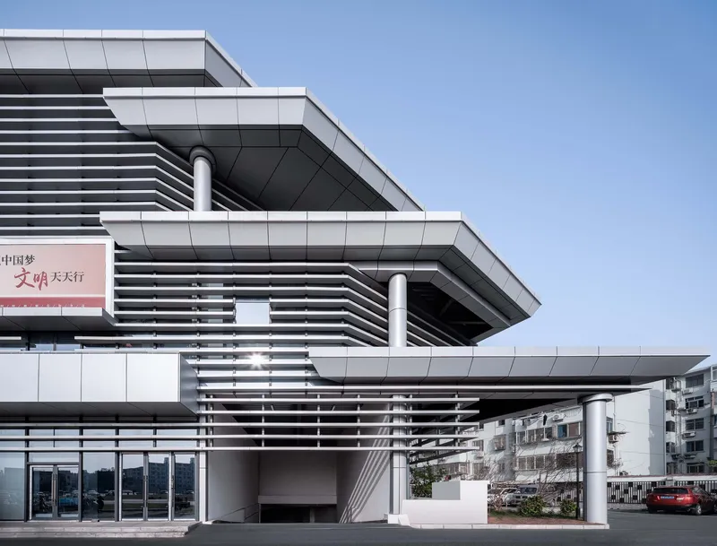 Facade detail showing stacked volumes with horizontal slats and cylindrical columns supporting cantilevered floors