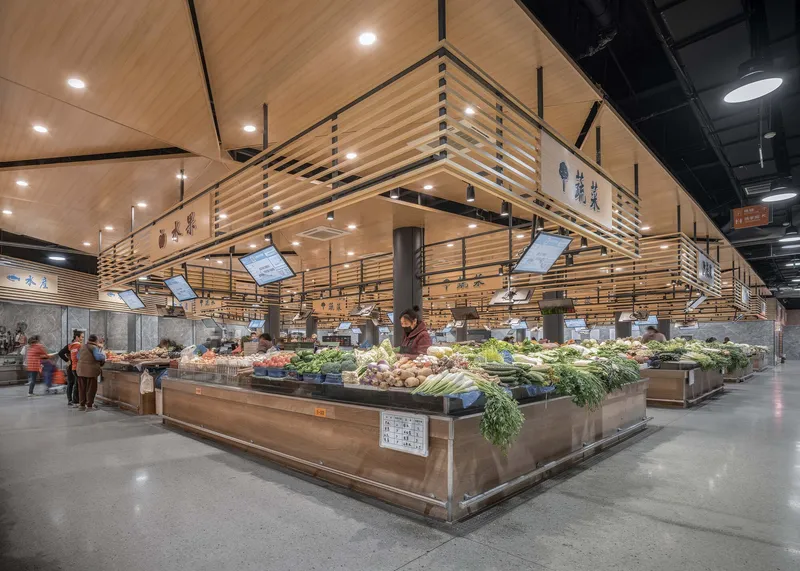 Interior market hall with timber-clad stalls displaying fresh produce beneath suspended wooden louvered canopies