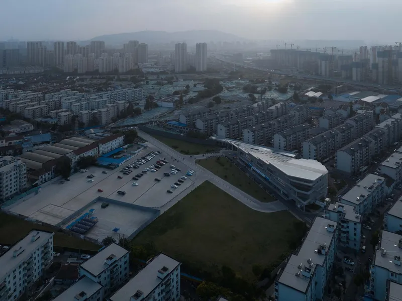 Drone view of the curved white roof among low-rise residential blocks in foggy morning light