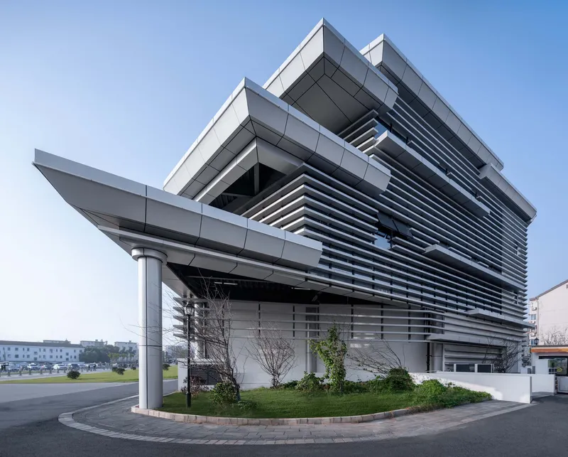 Corner view showing the cantilevered roof planes and horizontal louver screens with landscaped planting bed below