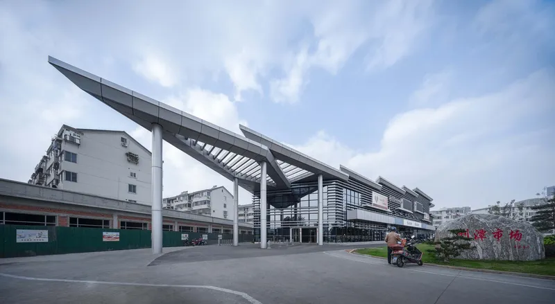 Long view of the elevated structure on white columns with upswept canopy edges and a motorcyclist passing