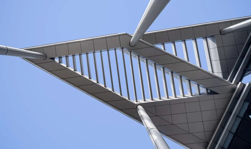 Detail of the triangular canopy underside with angled louver blades and white tubular support columns
